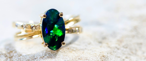 A Lightning Ridge black opal gold ring set with six shoulder set diamonds.